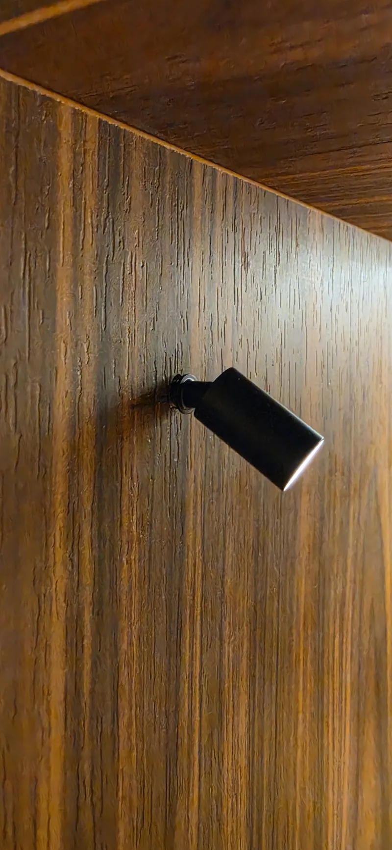 Detalhe do painel de marcenaria em tom escuro, com o desenho contínuo da superfície