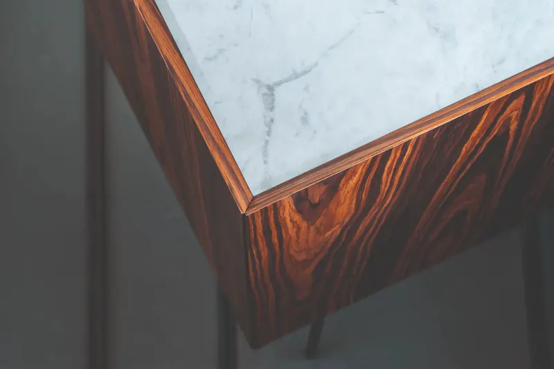 Detalhe de canto de aparador com tampo de pedra clara e lateral em tom amadeirado