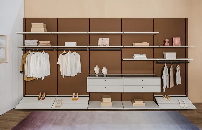 Closet aberto em vista frontal com painel marrom, prateleiras, cabideiros e sapateiras inclinadas