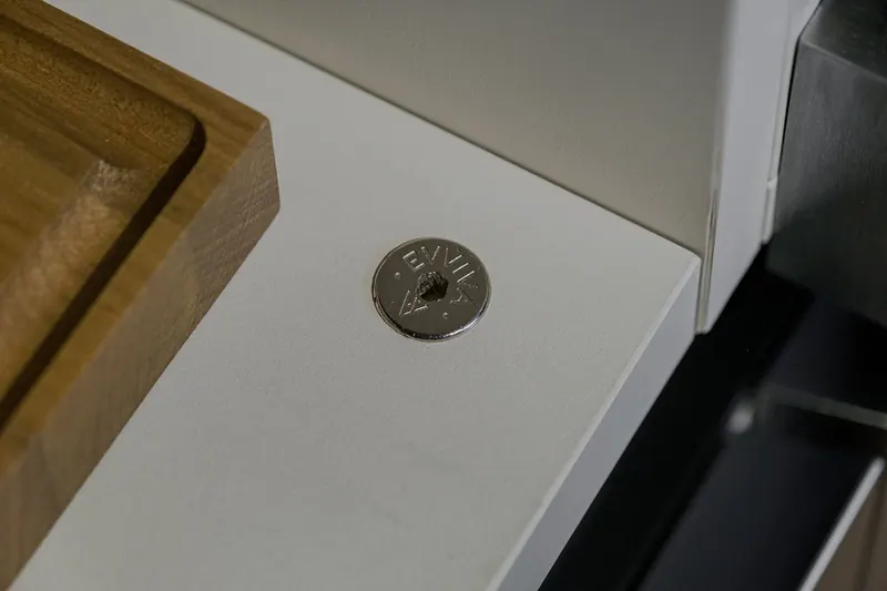 Detalhe de peça de fixação metálica gravada em lateral clara de armário