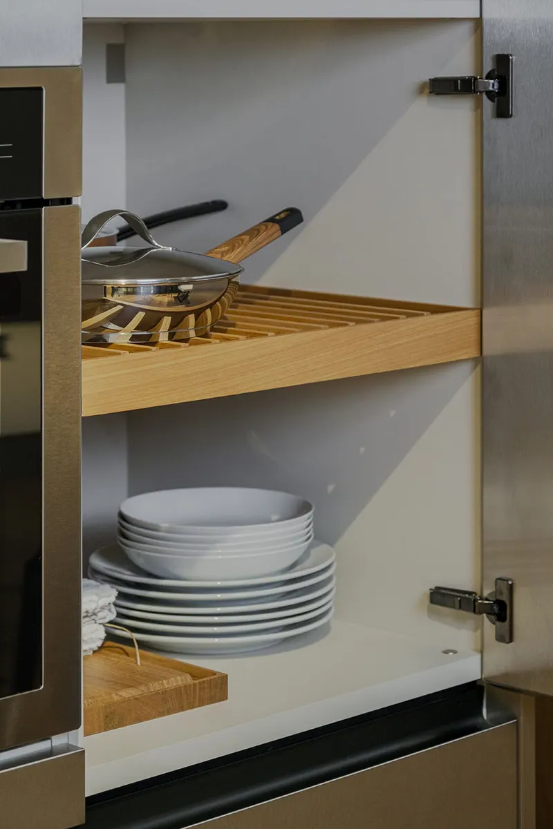 Interior de armário de cozinha com prateleira ripada para panelas e pratos empilhados