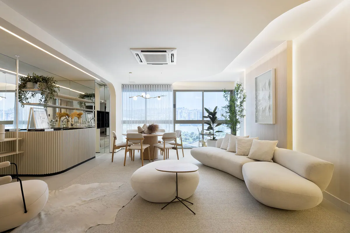 Sala ampla em tons claros com balcão curvo ripado, painel de parede com led e assento curvo