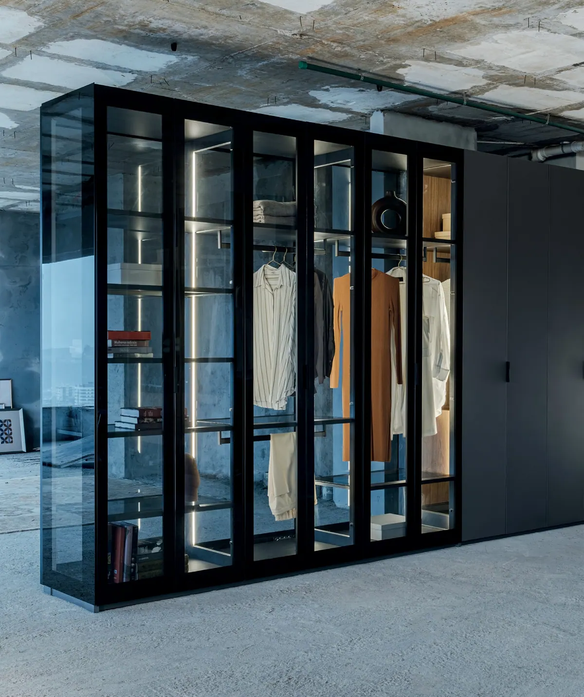 Closet com portas de vidro e perfis pretos ao lado de armário escuro fechado