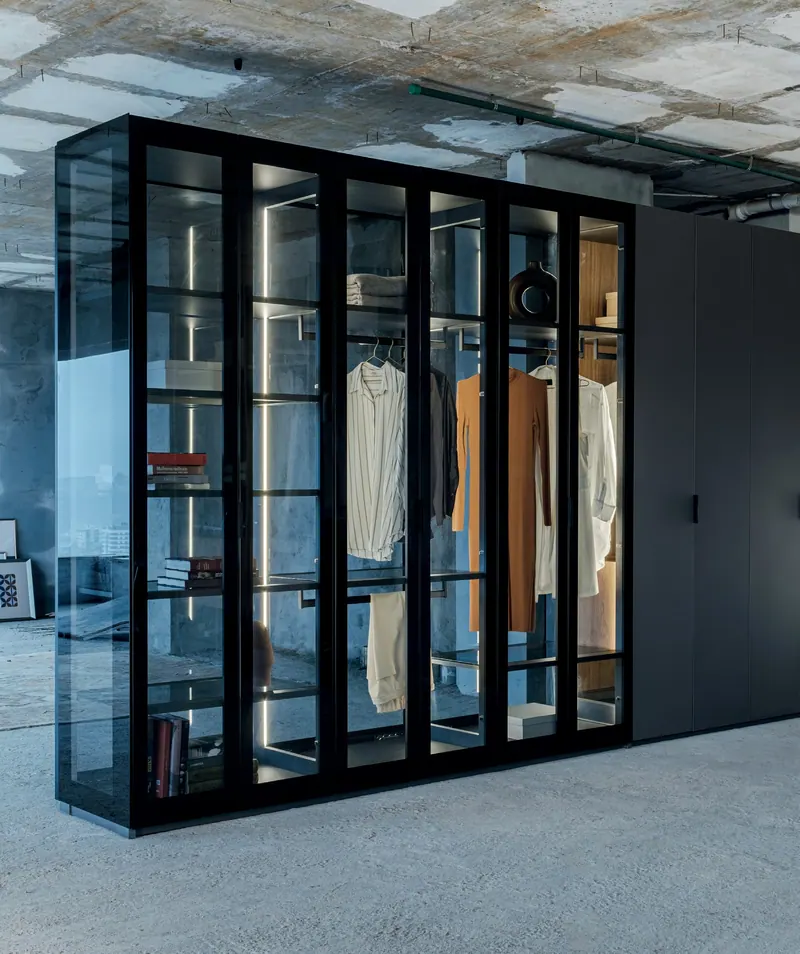 Closet com portas de vidro e perfis pretos ao lado de armário escuro fechado