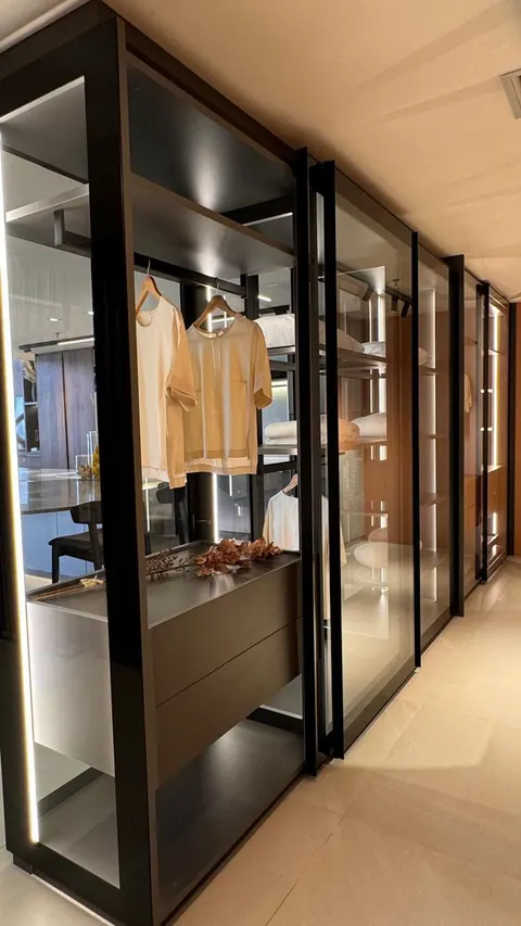 Closet comprido com portas de vidro e perfis pretos, cabideiro e gaveteiro, visto em perspectiva