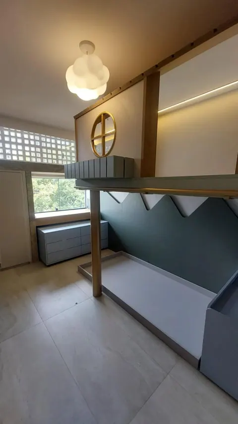 Quarto infantil com cama casinha elevada, painel verde recortado em montanhas e cômoda com gavetas