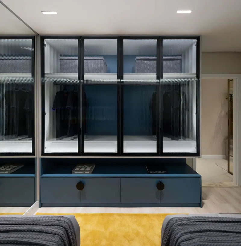 Roupeiro com portas de vidro canelado e moldura preta, interior iluminado